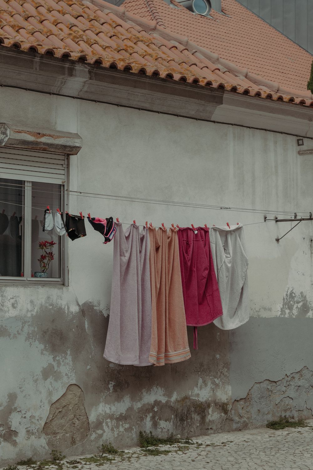 Vibrant clothes and towels hanging on an outdoor clothesline against a rustic wall.
